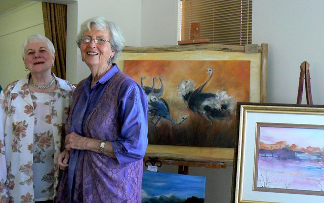 Vlnr is Hettie Oosthuizen en Olga Swanepoel by Olga se skildery, â€œParingsdansâ€ in die agtergrond